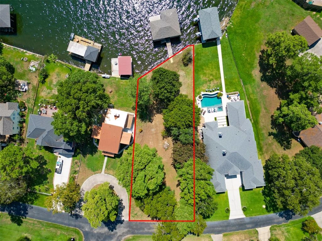 Overhead drone photograph of a tree-covered waterfront lot, with an approximate red outline between neighboring homes and docks.